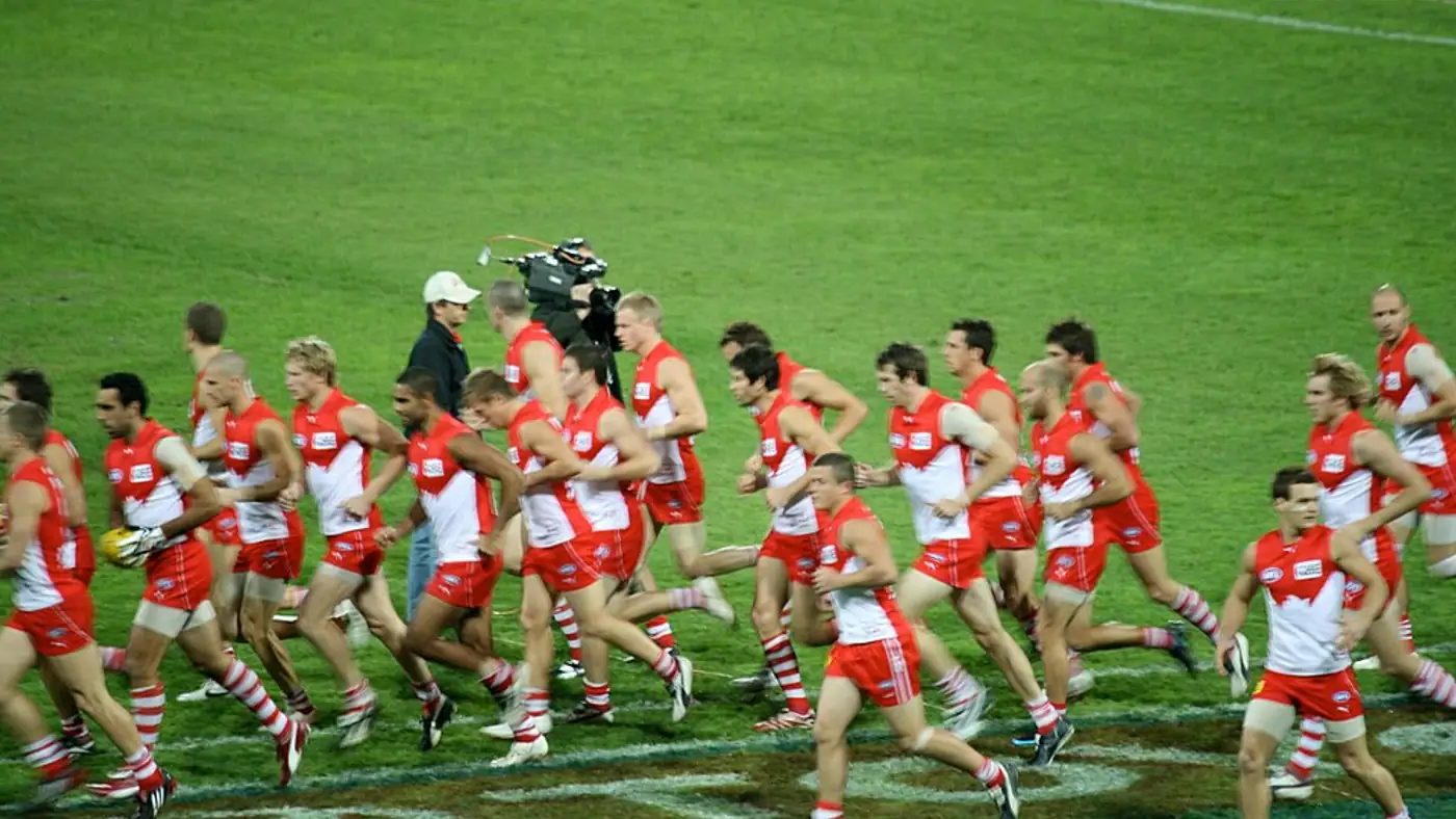 Schoolboy Australian rules players warming up on a grass oval in inner Sydney